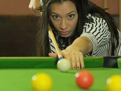 L/A CU young woman shooting pool billiards, balls in foreground, shooting to camera Stock Footage