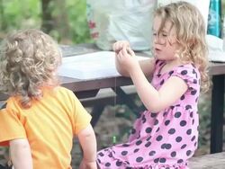 MS Little girl beading while little boy eating dry cereal in front of barbecue pit at picnic table / Toronto, Ontario, Canada Stock Footage