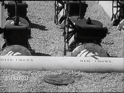 1947: STANDARD OIL (INDIANA): PIPELINE: Male worker checking pumps. VS Pipes on ground w/ labels: 'Red Crown' (automotive gas), 'Heater Oil', 'Power Fuel', male making notes, CU Smith-Meter fluid counting device tenths scrolling by. Instructional Video
