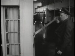 Guards stand in front of prison cells on Alcatraz as one guard pulls the level to open the door on a cell. News Clip