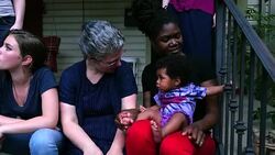 MS ZO Smiling lesbian couple sitting on front porch with family on summer evening Stock Footage