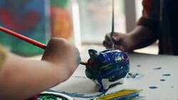 Two little boys painting piggy bank Stock Footage