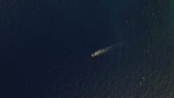 Birdseye view of small craft in evening light moves across the ocean Stock Footage