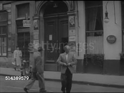 1952: ALLIED-OCCUPIED VIENNA: ECONOMY: DRAMATIZATION: VS Boys in living room reading, playing w/ truck, 'Albert Gertner' leaving for second job. Walking across street from apartment building, meeting & talking w/ illegal goods trader, dealer 'Franz X'. Instructional Video