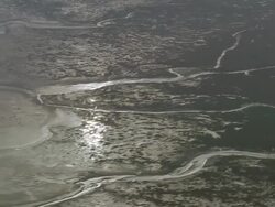 Aerial wide shot pan sun reflecting on Solway Firth mud flats/ Dumfries and Galloway, Scotland Stock Footage