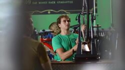 Young worker greets customer, takes wheel to spin on truing stand, and offers advice in bike repair shop Stock Footage