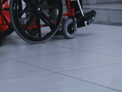 Patient sitting in wheel chair and a woman passing by Stock Footage