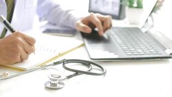 Doctor working with laptop and take a note and filling out medical document , UHD format , Dolly shot panning right to left movement Stock Footage