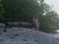 MS Man sitting on log with boy on his lap on beach / Montezuma, Puntarenas, Costa Rica Stock Footage