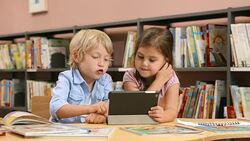 DS Little boy and girl using tablet in library Stock Footage