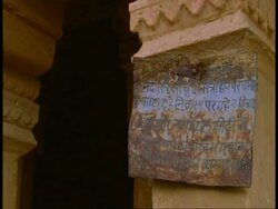 CU sign on pillar of Hindu temple, Hindu priest stands in background, Bandhavgarh National Park, India Stock Footage