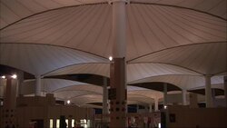 Commuters pass under the canopy of a bus terminal in Saudi Arabia. Stock Footage