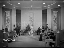 1948: BEVERLY HILLS, CALIFORNIA: WS 'Adrian' (Adrian Greenberg) designer clothing salon w/ convertibles parked on curb. VS Models modeling design gowns for clients in salon, seated women watching, model removing jacket from strapless gown. Instructional Video