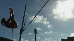 Female pole vaulter jumps and clears bar before pole knocks bar off Stock Footage