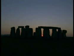 Dusk and Stonehenge - orange sun just visible between silhouetted stones, lilac/orange sky Stock Footage