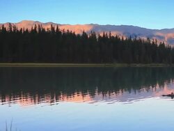 Mountains at sunset reflecting their glow in Alpine Lake Stock Footage