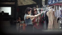 Two young women look at vintage dresses at outdoor Texas flea market Stock Footage