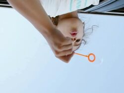 Girl blowing bubbles from car window, shot from below Stock Footage