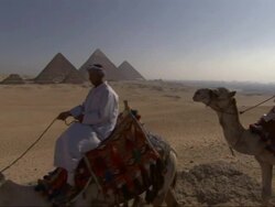 Wide Shot, tracking-left - Three men ride camels near the Great Pyramids in Egypt Stock Footage