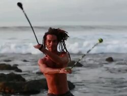 MS Rasta man spinninig poi balls with ocean / Montezuma, Punteranes, Costa Rica Stock Footage