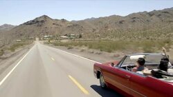 Friends drive through desert in red convertible Stock Footage