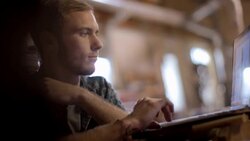 Young man working on laptop computer scrolls on touchpad and smiles Stock Footage