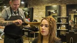 Male Hair stylist drying a female clients hair Stock Footage