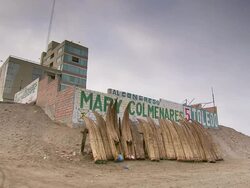 WS View of Traditional reed boats stacked on beach, residential block behind and brick wall with political advertisements painted / Pimentel, Lambayeque, Peru Stock Footage