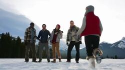 Friends jumping for joy hugging in snowy field Stock Footage