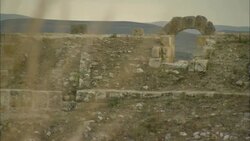 A stone archway frames mountains at the Oudna Amphitheater ruins in Tunisia. Stock Footage