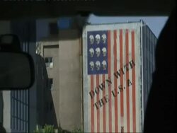 POV inside car, looking out to massive American flag painted on high rise building wall reading Down with the USA, Iran (sound available) Stock Footage