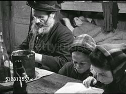 1945: POST-WAR RELIEF: WS People, adults & children walking in yard of Displaced Persons' Camp. REPRISAL: VS People sharing one room of wooden building, elder male in wooden bunk bed. AJDC Officer looking over male's paperwork w/ UNRRA officer at desk Instructional Video