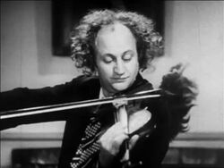 B/W 1936 Larry of the 3 Stooges playing violin with toupee attached to bow / feature Stock Footage