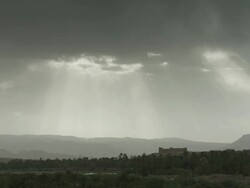 Birds fly across a dark Moroccan landscape, with sunlight streaking through the clouds. Stock Footage