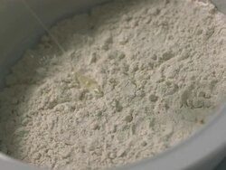 High speed Egg falling in to centre of bowl of flour, high angle Stock Footage