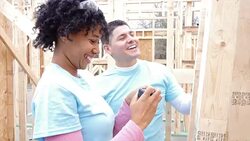 Volunteers marking measurements on house frame at construction site Stock Footage
