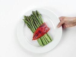 CU Woman hand entering setting down round white plate with green asparagus and red vegetable / Omaha, Nebraska, United States Stock Footage