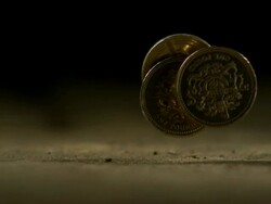 High Speed Three UK pound coins roll through frame Stock Footage