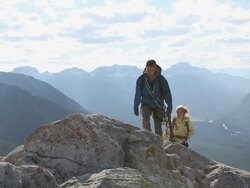 Climber couple approach mtn summit, exchange hugs Stock Footage