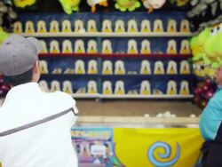 A man throws two softballs and hits the target at a midway attraction game at a State Fair Stock Footage