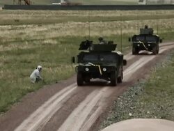 Shot of two Humvees driving by instructor dressed as a middle easterner. Stock Footage