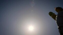 silohoueet of skater raising skateboard and hands in air with sun flares venice California skatepark Stock Footage