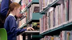 Girl studying at computer in school library Stock Footage