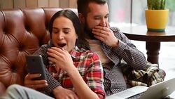 young couple sitting on sofa and using gadgets Stock Footage