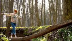 DS Woman crossing a creek over tree trunk Stock Footage