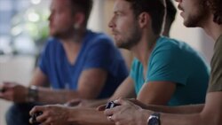 Guys sitting on couch playing video games and cheering Stock Footage