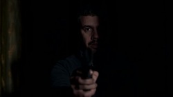 focus on robber in the darkness points the gun at the camera Stock Footage