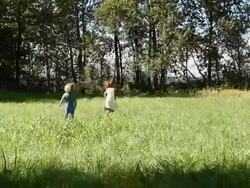 Young brother and sister running in a field Stock Footage