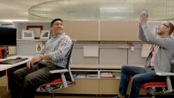 Two office-workers toss toy football back and forth in cubicle Stock Footage