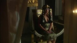 Ancient Egyptian dressed female seated or ornate chair with standing male wearing white robe, bowl of fire, curtains and columns Stock Footage